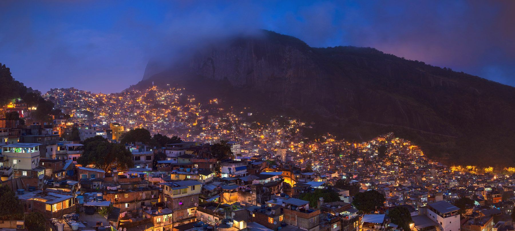 Favela da Rocinha ao entardecer, luzes acendendo pela encosta